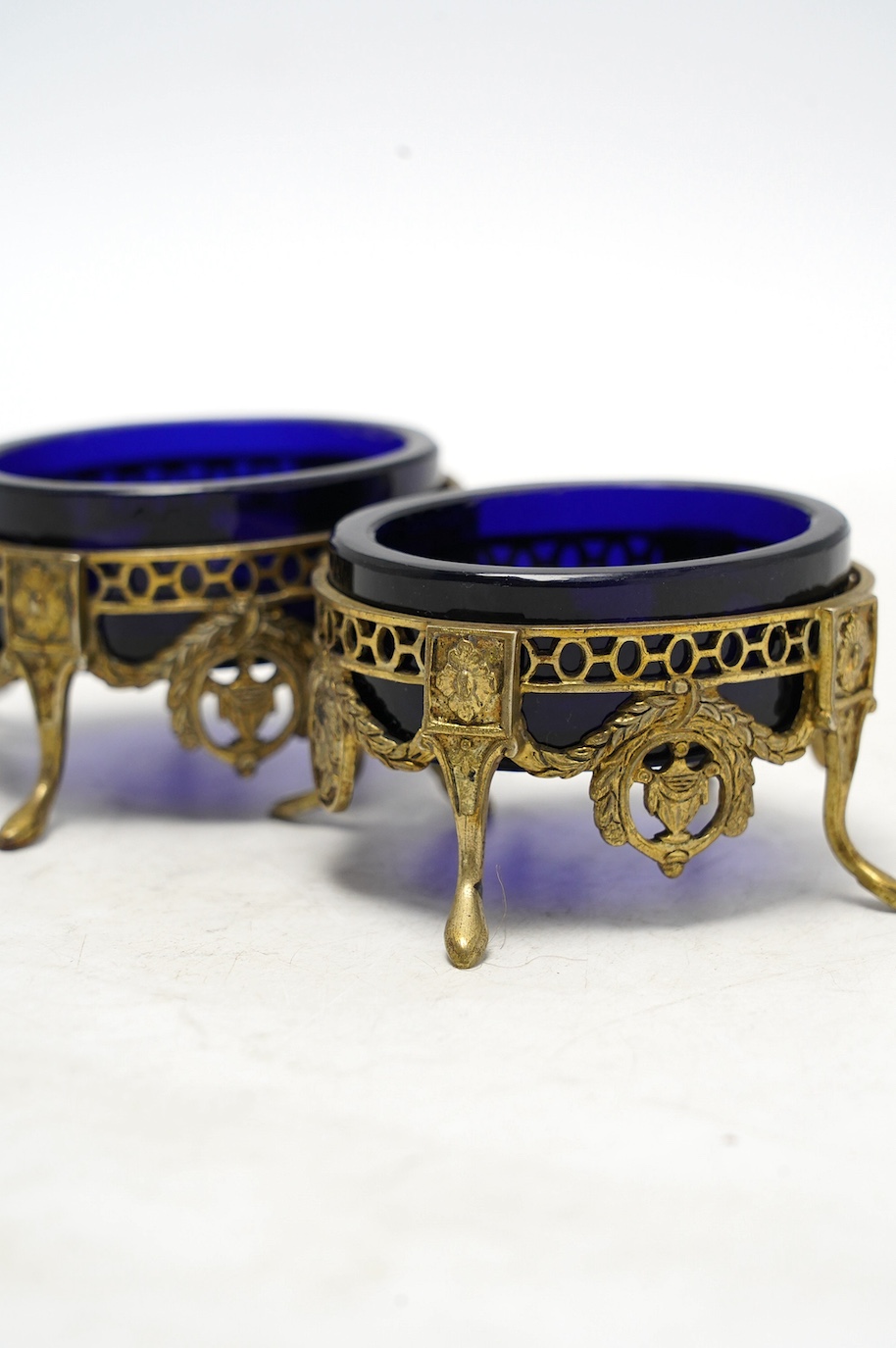 A pair of late 19th/early 20th century continental pierced gilt white metal oval salts, with blue glass liners, 69mm. Condition - fair